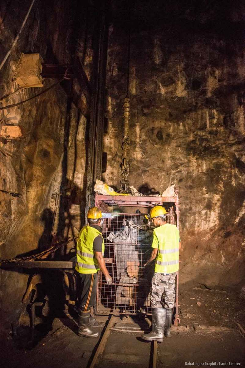 Two miners in high-visibility vests loading the cage at an underground station in the Kahatagaha mine.