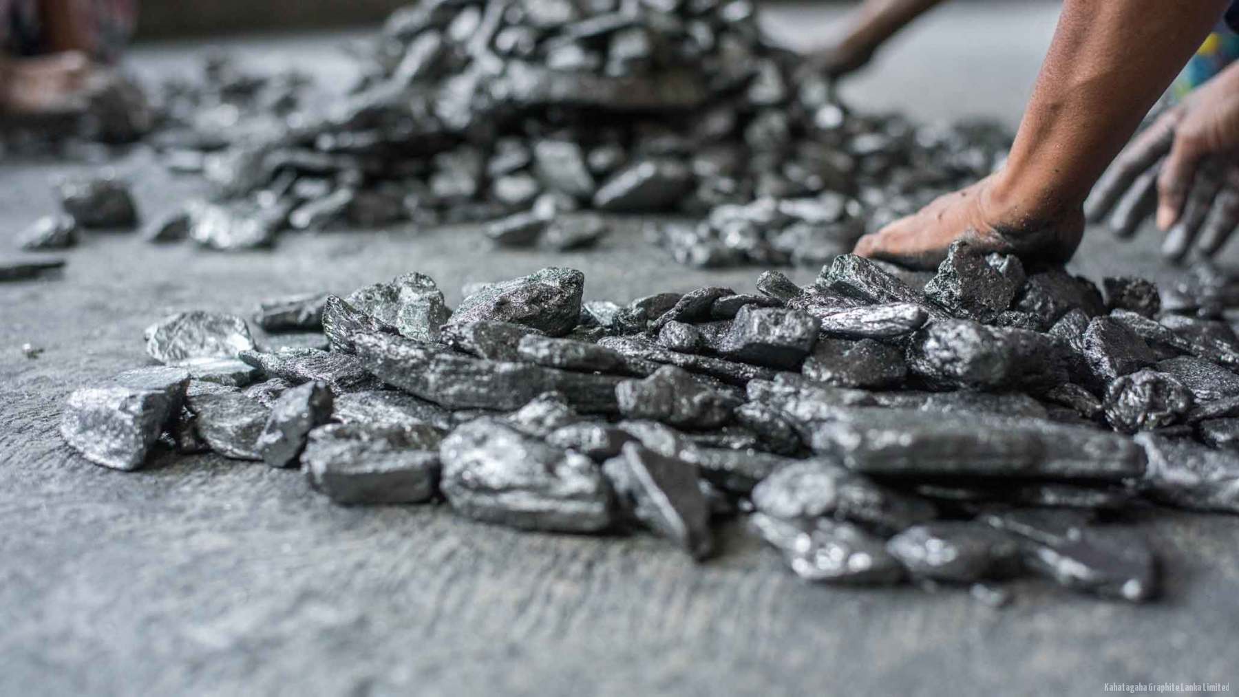Workers hand-sorting crystalline graphite into grades on the floor of the sorting shed.