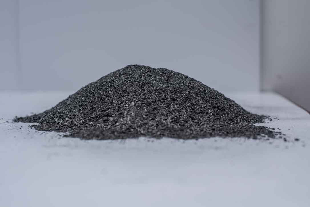 A cone of coarse graphite flake on a white surface.