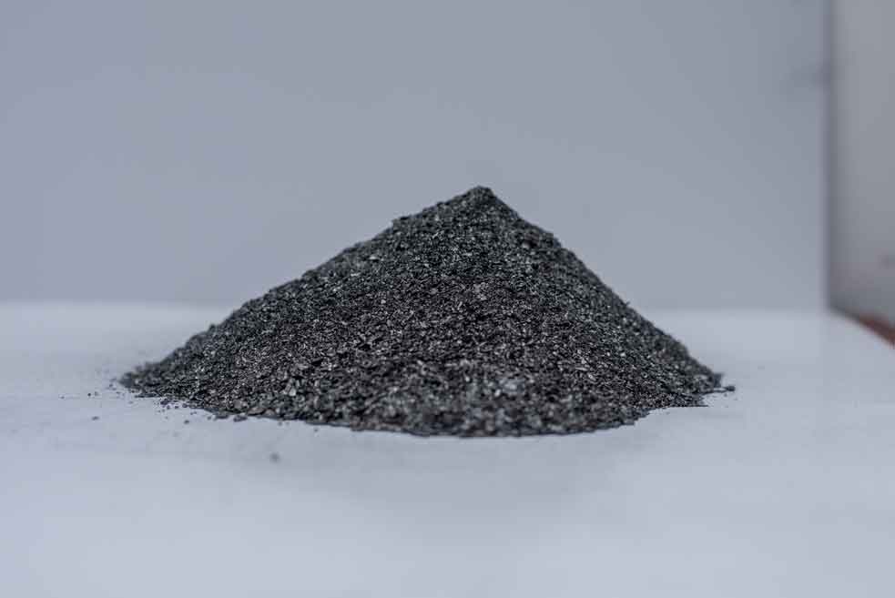 A cone of finely milled graphite powder on a white surface.